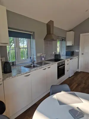 a kitchen with white cabinets and a sink at Spring Paddocks B&B in Furneux Pelham