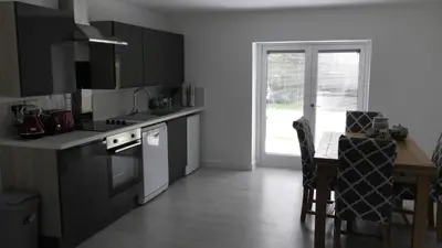 a kitchen with a sink and a table and a window at The Lodge Greatwood in Ipswich
