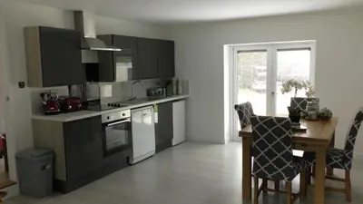 a kitchen with black cabinets and a table with a chair at The Lodge Greatwood in Ipswich