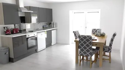 a kitchen with a wooden table and chairs and a table and a kitchen with at The Lodge Greatwood in Ipswich