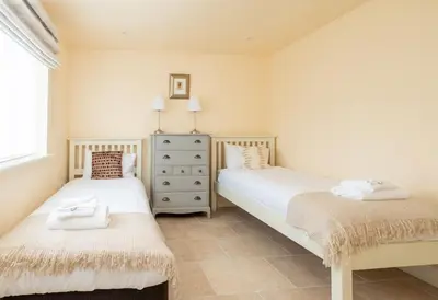 a bedroom with two beds and a dresser and a window at Willow House in Knodishall, Sleeps 7 - Only a short drive from Aldeburgh, Thorpeness & Snape Maltings - Managed by Aldeburgh Coastal Cottages in Aldringham