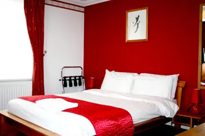 a red bedroom with a bed with a red wall at Hartland 2-Bedroom Apartments with Bfast and Parking in Southend-on-Sea