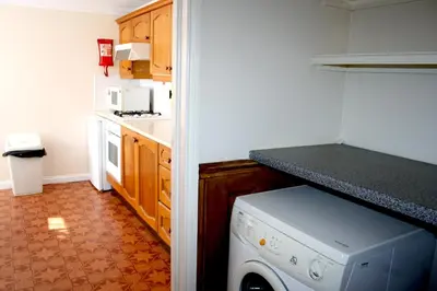 a small kitchen with a washer and dryer in it at Hartland 2-Bedroom Apartments with Bfast and Parking in Southend-on-Sea