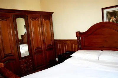 a bedroom with a bed and a large wooden cabinet at Hartland 2-Bedroom Apartments with Bfast and Parking in Southend-on-Sea