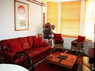 a living room with a red couch and a table at Hartland 2-Bedroom Apartments with Bfast and Parking in Southend-on-Sea