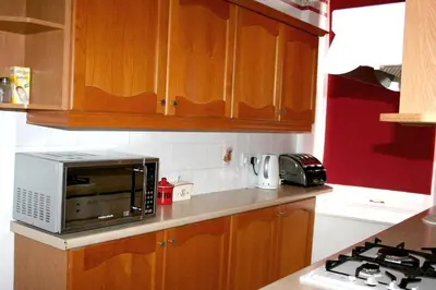 a kitchen with wooden cabinets and a microwave at Hartland 2-Bedroom Apartments with Bfast and Parking in Southend-on-Sea