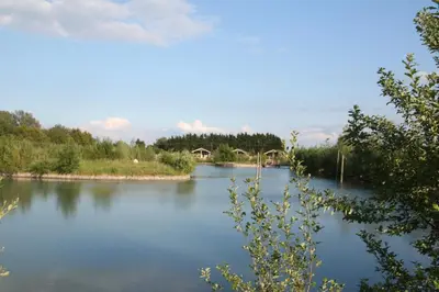 a view of a river with a bridge in the background at Waterside Lodges Cambridge in Cambridge