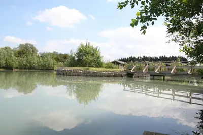 a body of water with a bridge and trees at Waterside Lodges Cambridge in Cambridge
