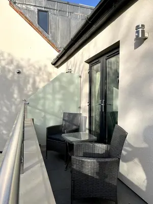 a patio with a table and chairs on a balcony at The Three Pickerels in Mepal