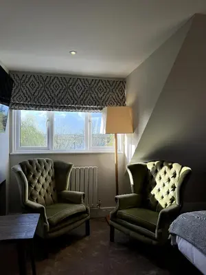 a bedroom with two chairs and a bed and a window at The Three Pickerels in Mepal