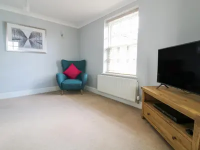a living room with a flat screen tv and a blue chair at The Hoist in Ely