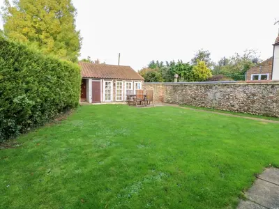 a yard with a stone wall and a table and chairs at The Old School in Wereham