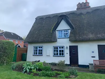 a white house with a thatched roof at Beaumont's Cottage in Cambridge