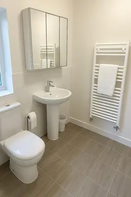 a white bathroom with a toilet and a sink at Stansted Coach House - Apartment Hotel in Elsenham