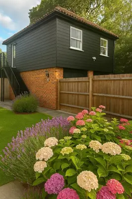 a black house with a fence and flowers at Stansted Coach House - Apartment Hotel in Elsenham
