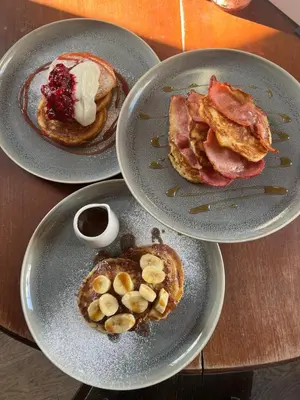 three plates of pancakes with bacon and fruit on a table at The Bell Inn, Rickinghall in Rickinghall