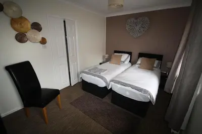 a small bedroom with two beds and a chair at Red Lion in Swaffham