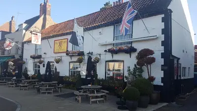 a building with tables and chairs in front of it at Red Lion in Swaffham