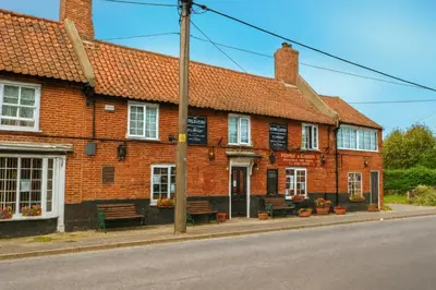 a brick building with benches in front of a street at The Horse and Groom Guest House in Swaffham