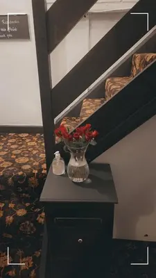 a vase with flowers on a table next to a staircase at The Horse and Groom Guest House in Swaffham