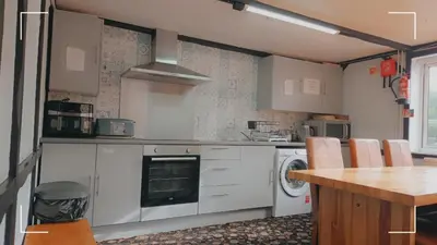 a kitchen with white cabinets and a table and a stove at The Horse and Groom Guest House in Swaffham
