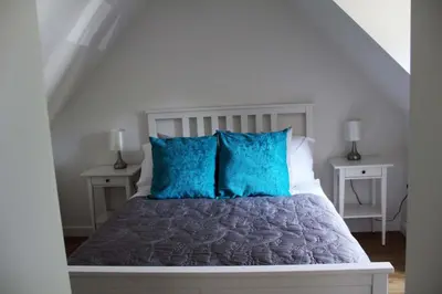 a bedroom with a bed with blue pillows at The Cart Lodge in Newmarket