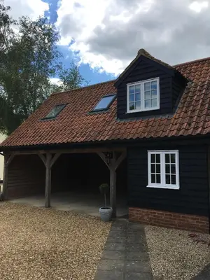a black house with a roof and a potted plant at The Cart Lodge in Newmarket
