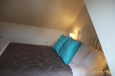 a bedroom with a bed with blue pillows on it at The Cart Lodge in Newmarket