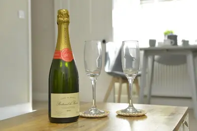 a bottle of wine and two glasses on a table at Old Green Chambers spacious town centre apartment with free parking! in St Ives