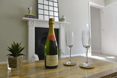 a bottle of wine and two glasses on a table at Old Green Chambers spacious town centre apartment with free parking! in St Ives
