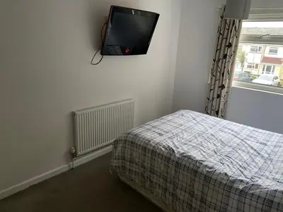a bedroom with a bed and a tv on the wall at Corporate Large Modern 4 to 5 Bedroom House in Bishops Stortford
