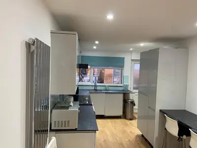 a kitchen with white cabinets and black counter tops at Corporate Large Modern 4 to 5 Bedroom House in Bishops Stortford