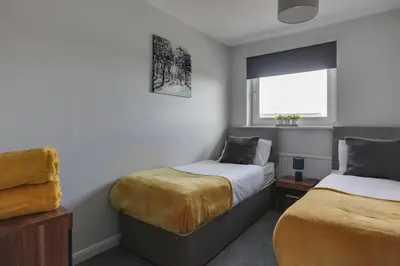 a bedroom with two beds and a window at Niche Sunrise Townhouse in Chelmsford