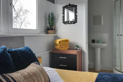 a bathroom with a bed and a sink and a mirror at Niche Sunrise Townhouse in Chelmsford