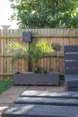 a planter with a plant in it next to a fence at Niche Sunrise Townhouse in Chelmsford