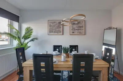 a dining room with a wooden table and chairs at Niche Sunrise Townhouse in Chelmsford