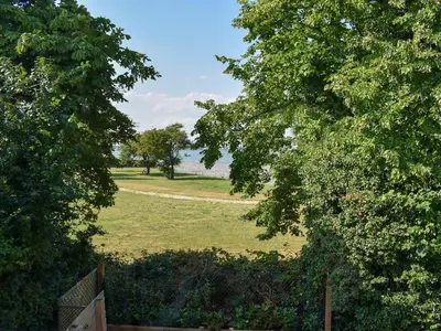 a field with trees and a path in the distance at Rainbows End in Saint Lawrence