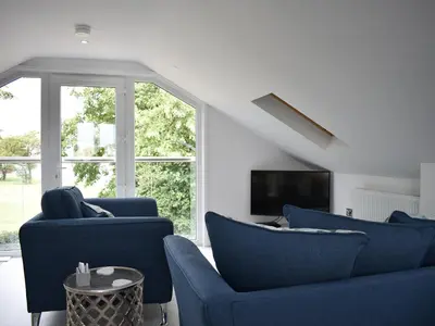 a living room with two blue chairs and a tv at Rainbows End in Saint Lawrence