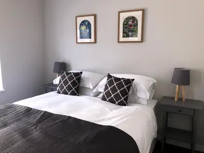 a bedroom with a bed with two tables and two pictures on the wall at Church View Bungay in Bungay