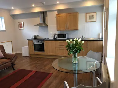 a kitchen with a glass table with a vase of flowers at Church View Bungay in Bungay