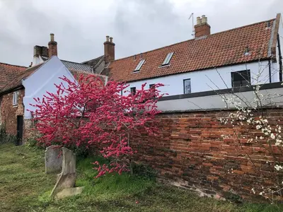 a brick building with a red tree in front of it at Church View Bungay in Bungay