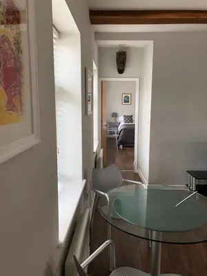 a living room with a glass table and a bedroom at Church View Bungay in Bungay