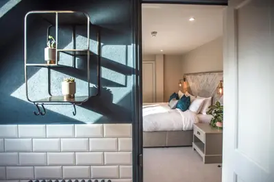 a bedroom with a bed and a bedroom with blue walls at The Lodge Duxford in Duxford