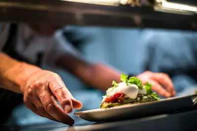 a person holding a plate of food on a table at The Lodge Duxford in Duxford