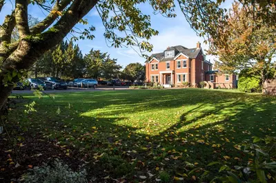 a house with a large lawn in front of it at The Lodge Duxford in Duxford