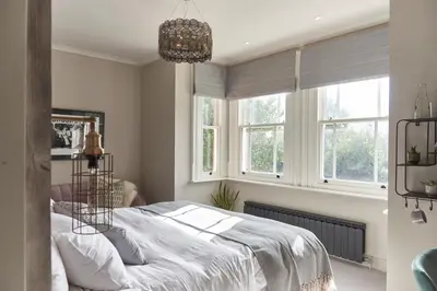 a bedroom with a bed and two windows at The Lodge Duxford in Duxford