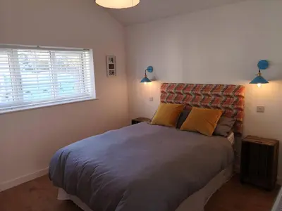 a bedroom with a large bed with two yellow pillows at The Bird House at Woodburn Cottage in Dedham