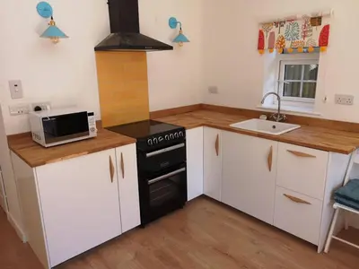 a kitchen with white cabinets and a black stove at The Bird House at Woodburn Cottage in Dedham