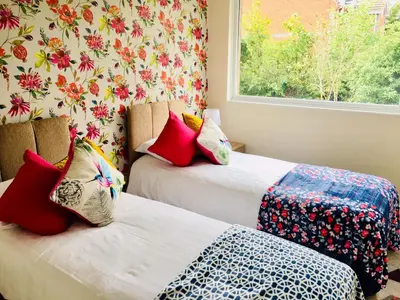 two beds in a room with a window at Homely & Cosy 3 Bed Birch Close House with Free Parking, Garden & Sleeps 8 in Cambridge
