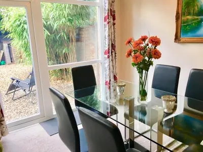 a glass dining room table with chairs and a vase of flowers at Homely & Cosy 3 Bed Birch Close House with Free Parking, Garden & Sleeps 8 in Cambridge